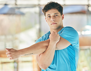 Image showing Portrait, fitness and man stretching arm in gym for health, wellness and flexibility. Sports face, training and male athlete stretch, warm up and getting ready to start workout, exercise or running.