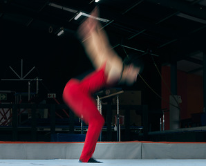 Image showing Moving, gymnastics and jump with man in stadium for sports, speed and motion blur. Workout, action and challenge with flexible athlete training in gym arena for performance, exercise and health