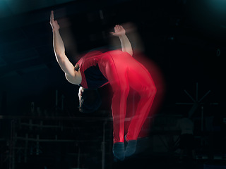 Image showing Sports, gymnastics and jump with man in stadium for fitness, speed and motion blur. Workout, action and challenge with flexible athlete training in gym arena for performance, exercise and health