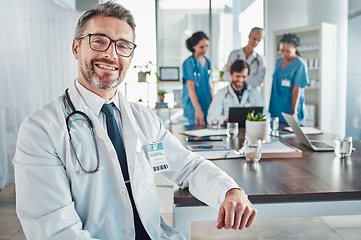 Image showing Healthcare, smile and portrait of senior doctor at desk in teaching hospital office with nurses and medical students. Health, medicine and leadership with mature mentor and smiling man at clinic.