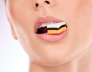 Image showing Liquorice, woman eating and mouth with makeup and cosmetics in an isolated studio. White background, sweet food and candy product with hungry female model with cheat meal and sugar for dessert