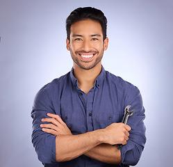 Image showing Man, studio and portrait with tools or spanner for handyman, maintenance or repair work with a smile. Happy asian handy man person smile on purple background for engineer, mechanic or technician job