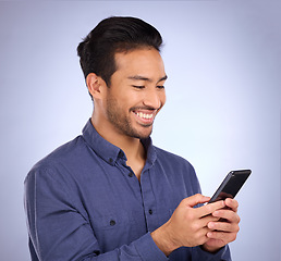 Image showing Business asian man, phone and smile for social media, communication or texting against studio background. Happy male smiling on mobile smartphone in networking for chatting, browsing or app on mockup