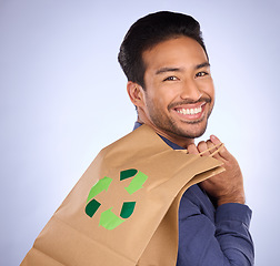 Image showing Man in portrait, happy and recycling paper bag, environment and sustainable shopping on studio background. Eco friendly, green and climate change awareness in retail, sustainability and recycle logo