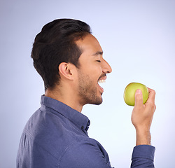 Image showing Man, face and profile, eating apple with nutrition, food and health, diet and fruit in hand on studio background. Healthy lifestyle, wellness and detox to lose weight, organic and vegan with fibre