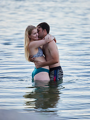 Image showing Kiss, hug and couple swimming by the beach for bonding, quality time and holiday by ocean. Romance, happy and man and woman with affection, hugging and enjoying a swim together in the sea on vacation