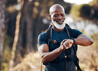 Image showing Hiking, man and watch for time in nature forest trekking for fitness and cardio exercise. Senior black person smile while walking outdoor with backpack and smartwatch for travel, health and wellness