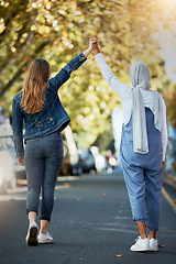 Image showing Support, solidarity and lesbian couple holding hands in the street for walking, trust and love. Equality, freedom and back of a Muslim woman with a girl showing affection in lgbt relationship