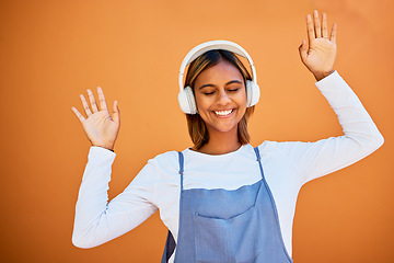 Image showing Dance, happy and woman with headphones music isolated on an orange studio background. Smile, free and carefree dancing girl listening to audio, podcast or sound for entertainment and freedom