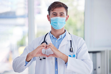 Image showing Covid, portrait and doctor with hand heart sign at hospital for healthcare, innovation and symbol of trust. Emoji, hands and face of cardiovascular surgeon with mask for corona compliance at a clinic