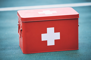 Image showing First aid, kit and health equipment for medical emergency, response and treatment kit isolated on a blurred background. Red, cross and medicine on a sports ground or court for fast health or cure