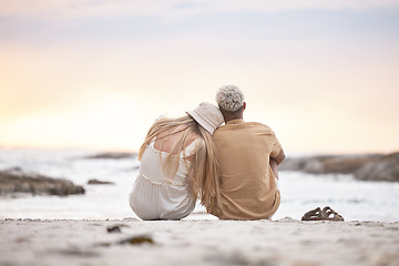 Image showing Rear view of a young couple taking a break at the beach during sunset. Caucasian female and her mixed race boyfriend relaxing and enjoying the view at the beach