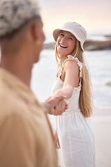 Image showing Closeup portrait of an young affectionate mixed race couple standing on the beach holding hands and smiling during sunset outdoors. Hispanic man and caucasian woman showing love and affection on a ro