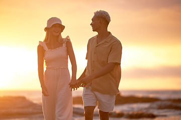 Image showing Closeup portrait of an young affectionate mixed race couple standing on the beach and smiling during sunset outdoors. Hispanic man and caucasian woman showing love and affection on a romantic date at