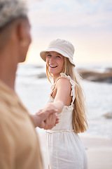 Image showing Closeup portrait of an young affectionate mixed race couple standing on the beach holding hands and smiling during sunset outdoors. Hispanic man and caucasian woman showing love and affection on a ro