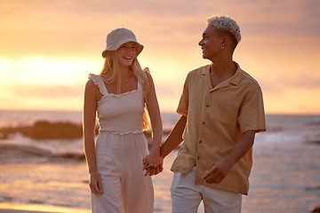 Image showing Closeup portrait of an young affectionate mixed race couple standing on the beach and smiling during sunset outdoors. Hispanic man and caucasian woman showing love and affection on a romantic date at