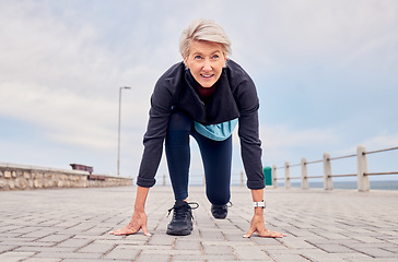 Image showing Senior woman, starting position and running outdoor at beach promenade, runner exercise or sky mockup. Elderly lady ready to run, cardio and fitness training for mindset of sports, marathon or energy