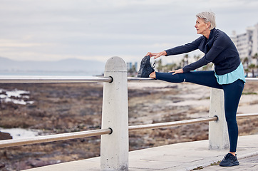 Image showing Senior woman, fitness and stretching at beach sidewalk for energy, wellness and healthy workout on sky mockup. Elderly lady, exercise and warm up legs at sea promenade for sports, thinking or running