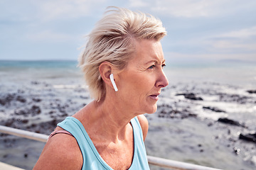 Image showing Senior woman running at beach with earphones for energy, wellness or healthy workout. Elderly female, exercise and fitness at ocean of sports, cardio marathon or listening to music for strong mindset