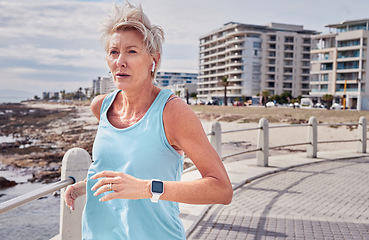 Image showing Senior woman, fitness and running at beach promenade for energy, wellness and healthy workout in Miami. Elderly female, earphones and runner at sea for sports, cardio exercise and marathon training