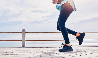 Image showing Legs of woman, fitness and running at promenade beach for energy, wellness and sky mockup. Closeup lady, runner shoes and outdoor exercise at sea for marathon training, sports and workout performance