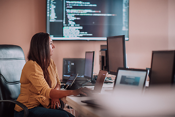 Image showing A businesswoman sitting in a programmer's office surrounded by computers, showing her expertise and dedication to technology.