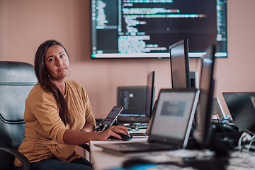 Image showing A businesswoman sitting in a programmer's office surrounded by computers, showing her expertise and dedication to technology.