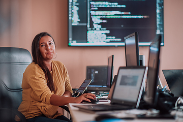 Image showing A businesswoman sitting in a programmer's office surrounded by computers, showing her expertise and dedication to technology.