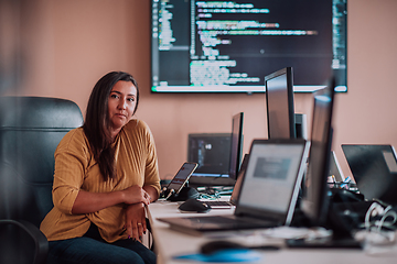 Image showing A businesswoman sitting in a programmer's office surrounded by computers, showing her expertise and dedication to technology.