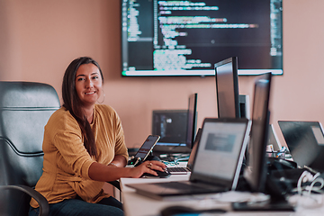 Image showing A businesswoman sitting in a programmer's office surrounded by computers, showing her expertise and dedication to technology.