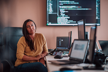 Image showing A businesswoman sitting in a programmer's office surrounded by computers, showing her expertise and dedication to technology.