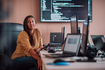 Image showing A businesswoman sitting in a programmer's office surrounded by computers, showing her expertise and dedication to technology.