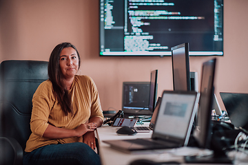 Image showing A businesswoman sitting in a programmer's office surrounded by computers, showing her expertise and dedication to technology.