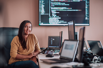 Image showing A businesswoman sitting in a programmer's office surrounded by computers, showing her expertise and dedication to technology.