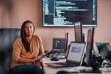 Image showing A businesswoman sitting in a programmer's office surrounded by computers, showing her expertise and dedication to technology.