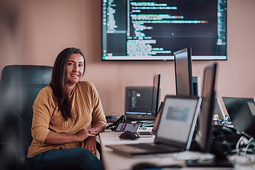 Image showing A businesswoman sitting in a programmer's office surrounded by computers, showing her expertise and dedication to technology.