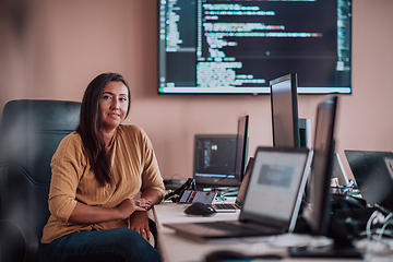 Image showing A businesswoman sitting in a programmer's office surrounded by computers, showing her expertise and dedication to technology.