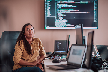 Image showing A businesswoman sitting in a programmer's office surrounded by computers, showing her expertise and dedication to technology.