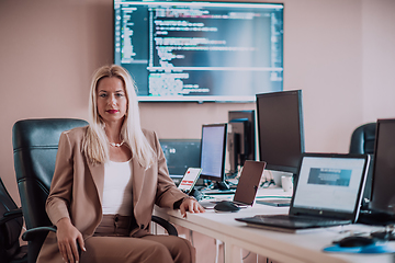 Image showing A businesswoman sitting in a programmer's office surrounded by computers, showing her expertise and dedication to technology.