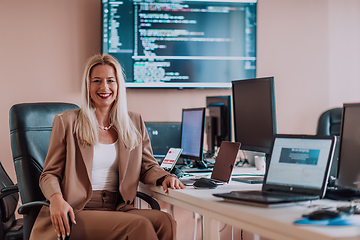 Image showing A businesswoman sitting in a programmer's office surrounded by computers, showing her expertise and dedication to technology.