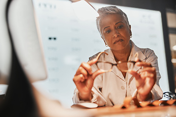 Image showing Glasses, optometry and check with a mature woman optician looking at a pair of frame spectacles in the office. Eyewear, healthcare and examine with a female optometrist checking prescription lenses