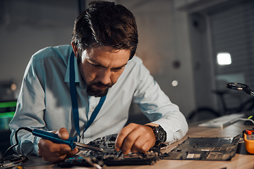 Image showing Concentration man, it or soldering motherboard in engineering workshop for night database fixing. Technician, circuit board or tools in repair, maintenance upgrade or information technology industry