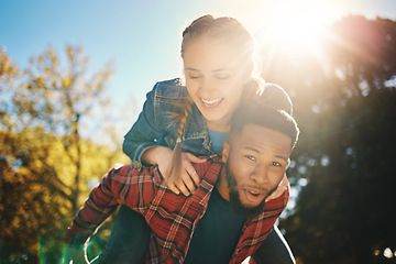 Image showing Interracial couple, sunshine and piggyback in park, summer and outdoor date together for happiness, smile and nature. Happy man carrying woman in garden for love, care and relax for diversity partner