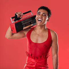 Image showing Happy, man and boombox radio in studio for gay, pride and vogue aesthetic with retro 80s tech by red background. Lgbtq model, vintage fashion and music with happiness, listening and comic laughing