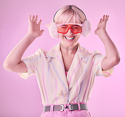 Image showing Fashion, beauty and happy woman isolated on pink background excited, wow and dancing on creative aesthetic. Earmuffs, clothes and cool, retro and punk sunglasses of gen z model or person in studio