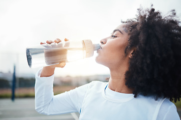 Image showing Black woman, sports and drinking water at court during training, workout and sport exercise outdoors. Fitness, thirsty and girl with bottle for wellness, hydration and recovery during practice