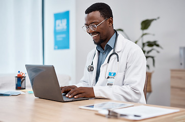 Image showing Black man, doctor and laptop with smile in healthcare for research, medicine or PHD at clinic desk. Happy African American male medical professional smiling, working or typing on computer at hospital