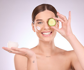 Image showing Woman, face and cucumber with moisturizer for skincare nutrition, cream or healthy diet against gray studio background. Portrait of female with vegetable or creme for natural organic facial cosmetics