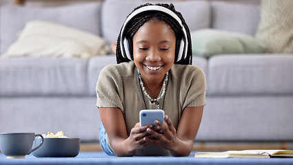 Image showing Black woman, student and phone with smile for elearning, education or entertainment by living room sofa at home. Happy African American female learner smiling on mobile smartphone lying on floor