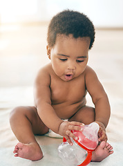 Image showing Kids, black baby and girl with a bottle sitting on a blanket on the floor of a home for child development. Children, cute and curious with a newborn infant learning or growing alone in a house